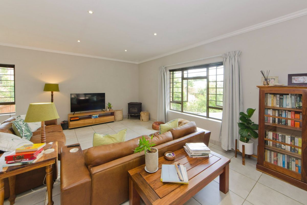 A comfortable living room featuring tiled flooring, recessed downlights, and a freestanding fireplace, with large windows providing natural light.
