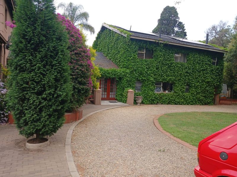 Front view of a two-story house featuring a gravel driveway, paved walkway, and a facade covered in mature ivy.