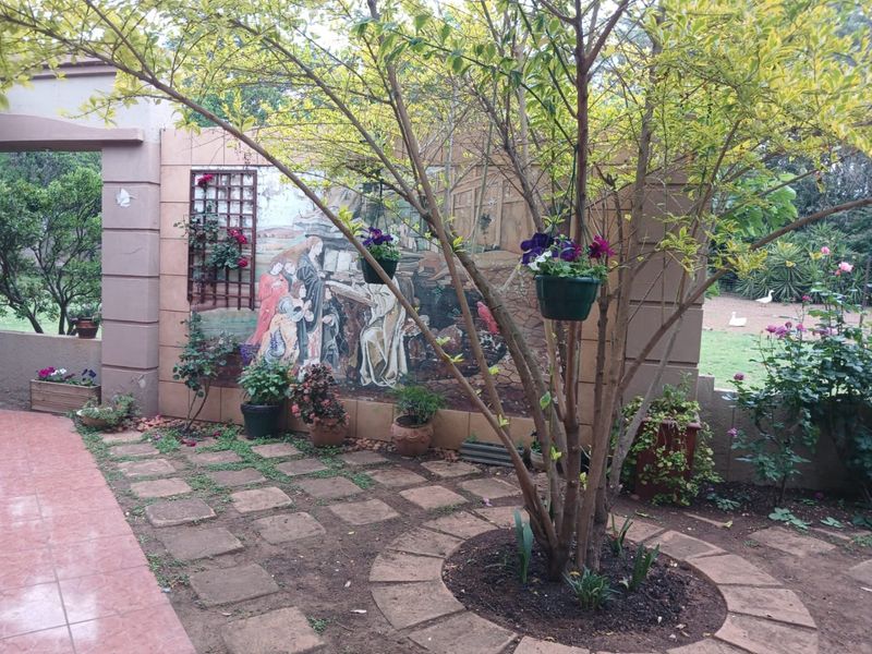 A landscaped garden area featuring stone paving, a decorative wall mural, and a tiled patio section, providing a pleasant outdoor space.