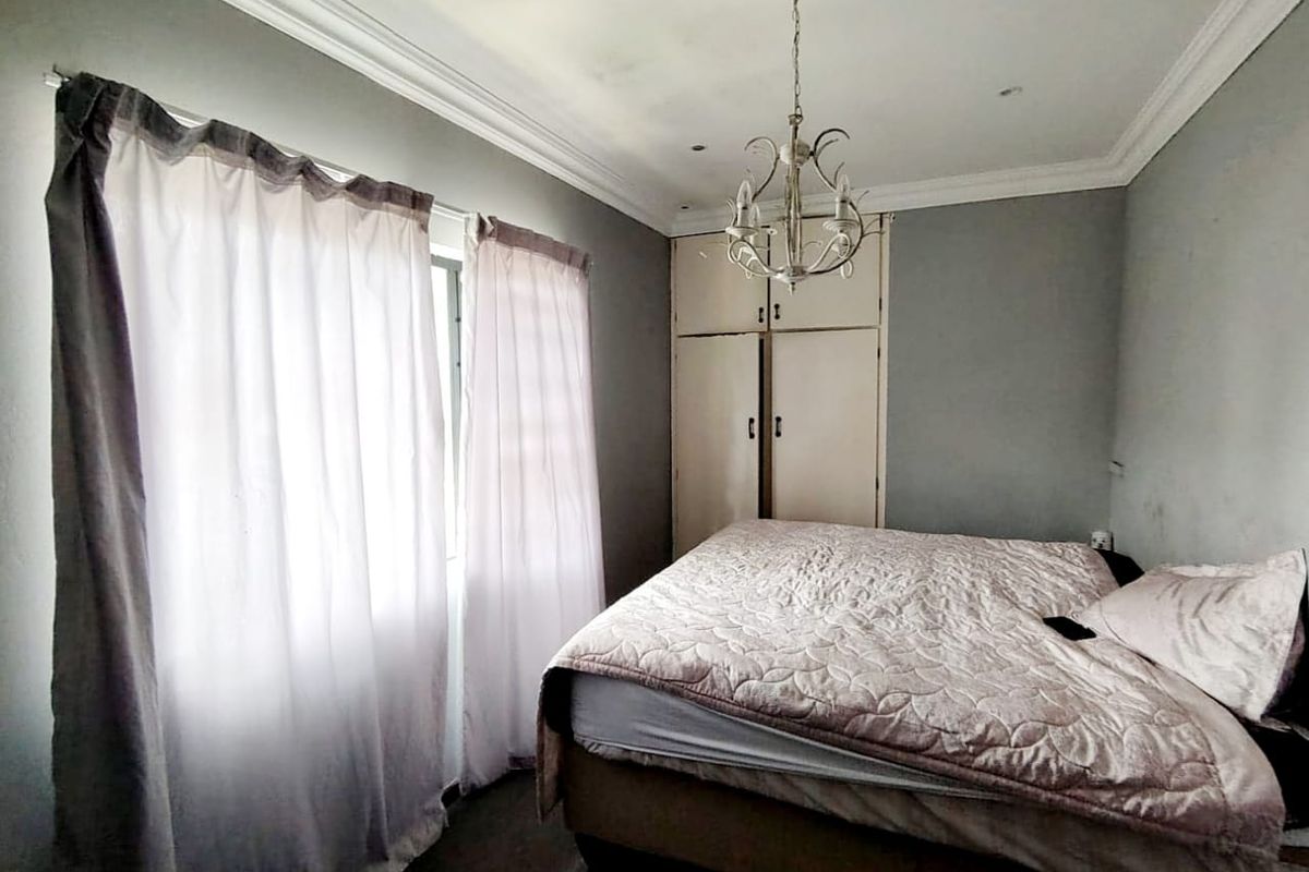 A bedroom featuring built-in cupboards, crown molding, and a central light fixture, offering a functional space with potential for cosmetic updates.