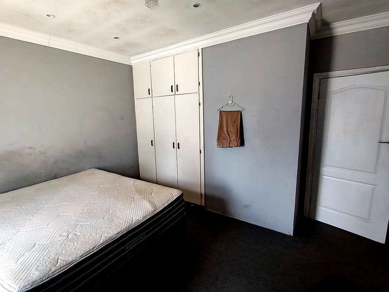 A bedroom featuring built-in cupboards, crown molding, and recessed lighting. The room requires cosmetic attention to address visible wall and ceiling staining.