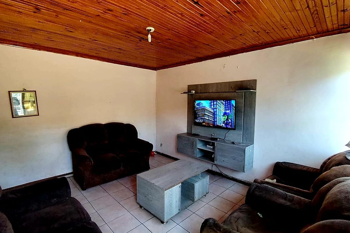 A living room featuring ceramic floor tiles and a timber tongue and groove ceiling, equipped with a built-in media console.