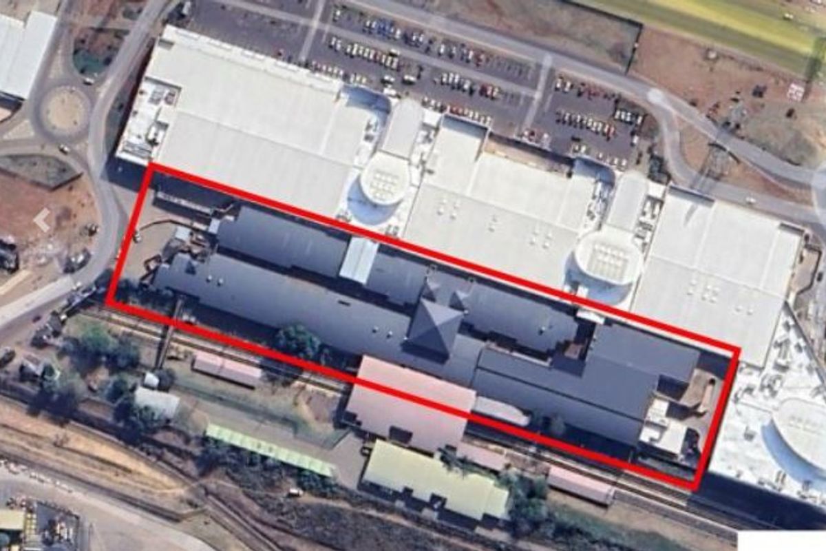 Aerial view of a commercial property complex featuring large industrial-style roofing and surrounding parking infrastructure.