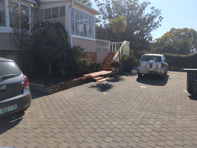 Front exterior view of the house featuring a paved driveway, stone retaining wall, and a concrete staircase leading to the entrance.