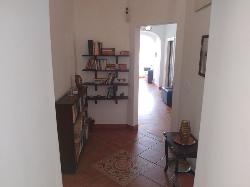 A tiled hallway featuring a decorative floor inlay and an arched transition leading into the adjacent living space.