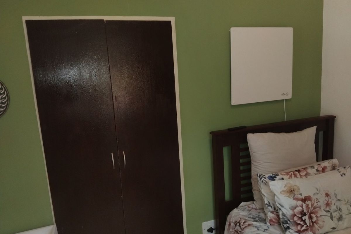 A bedroom featuring a built-in wardrobe and a wall-mounted electric heater.