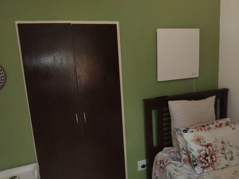 A bedroom featuring a built-in wardrobe and a wall-mounted electric heater.