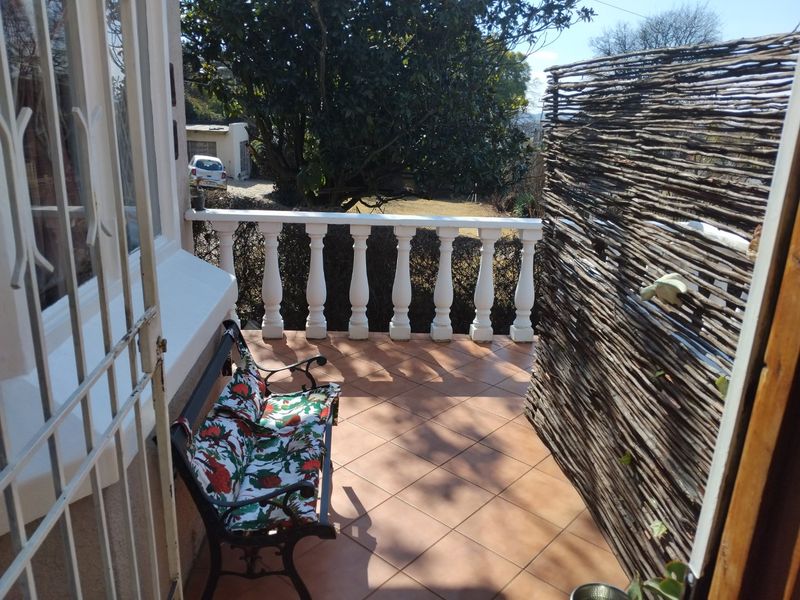 A covered patio area featuring tiled flooring and a classic balustrade, providing an outdoor space accessible from the main dwelling.