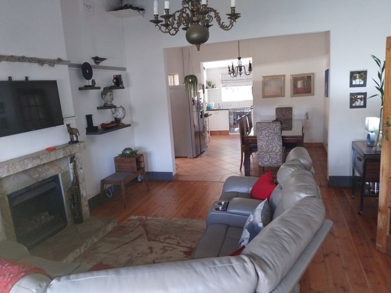 Open-plan living and dining area featuring a stone fireplace, hardwood floors, and a connected kitchen with tiled flooring.