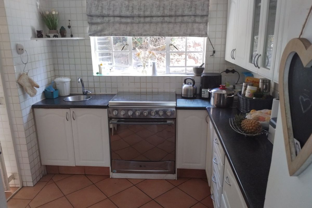 A functional kitchen featuring white cabinetry, a stainless steel stove, dark countertops, and tiled finishes throughout.