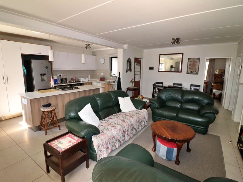 Open-plan living area featuring a modern kitchen with a central island, gas hob, and tiled flooring, seamlessly connecting to the dining and lounge space.