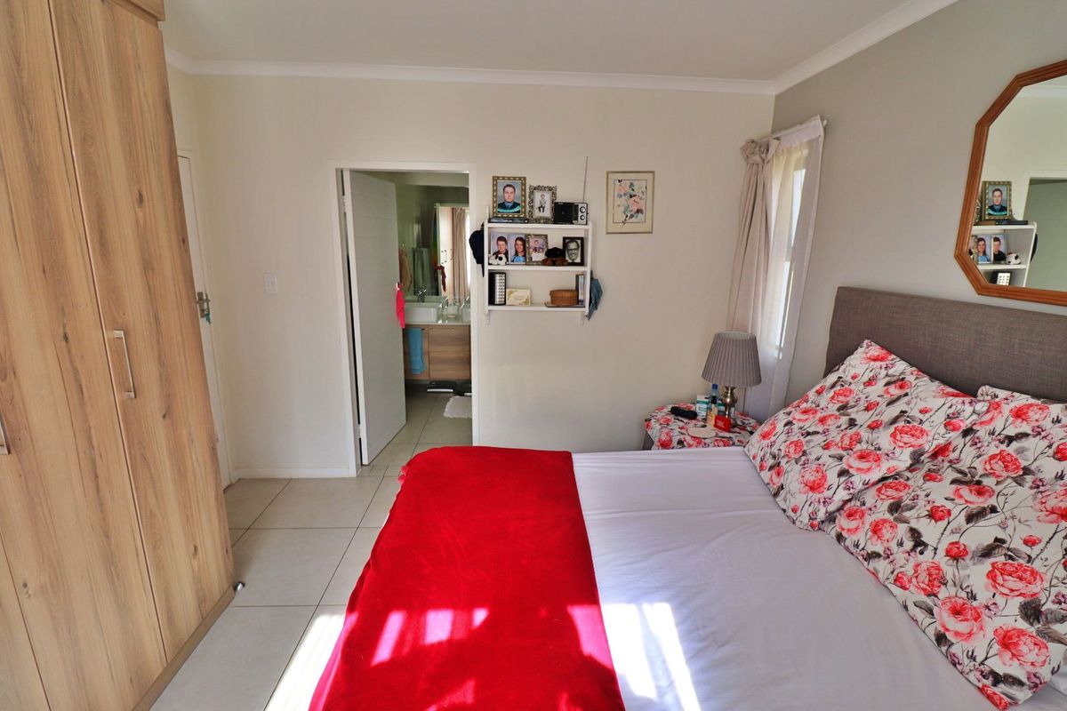 A well-maintained bedroom featuring tiled flooring, a built-in wardrobe, and direct access to an en-suite bathroom.