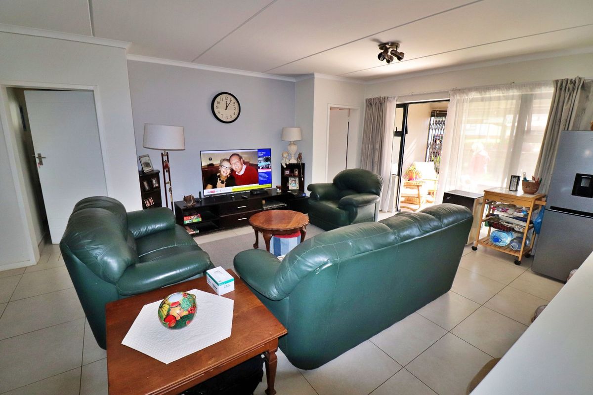 A spacious living room featuring neutral tiled flooring and a sliding glass door providing access to an outdoor patio area.