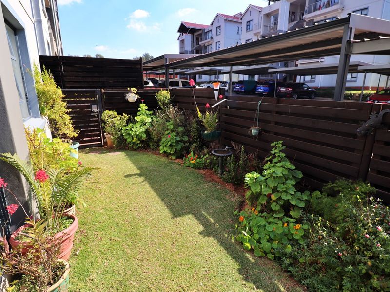 A private, well-maintained garden area featuring a manicured lawn, landscaped garden beds, and timber privacy fencing.