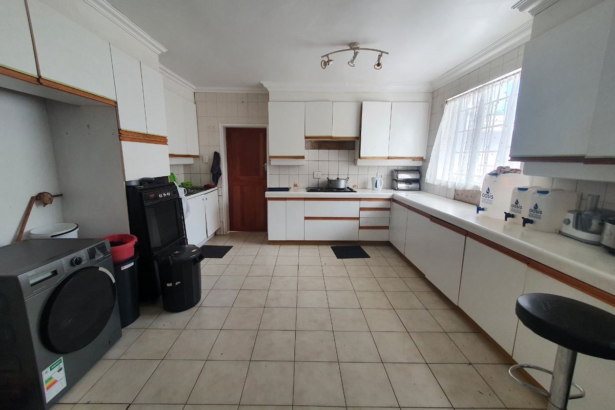 A spacious kitchen featuring extensive built-in cabinetry, tiled flooring, and a functional layout with integrated cooking appliances and ample counter space.