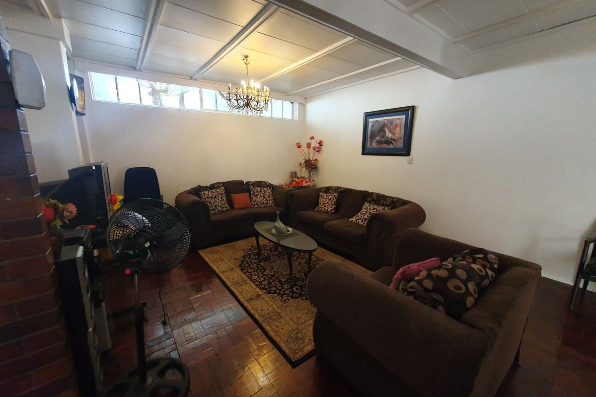 Spacious living room featuring warm hardwood parquet flooring, a brick fireplace, and a unique exposed beam ceiling with high-level clerestory windows.
