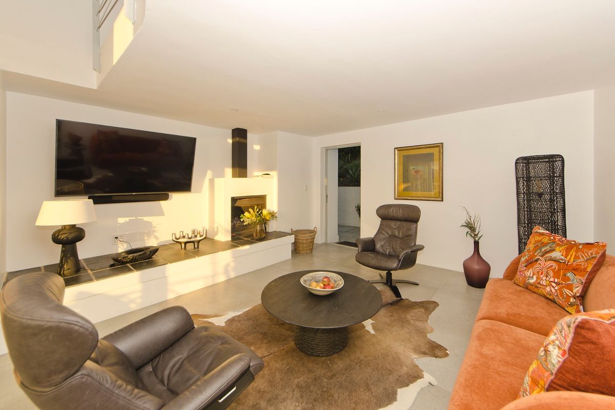 Spacious living room featuring a built-in fireplace with a tiled hearth, sleek flooring, and direct access to an outdoor area.