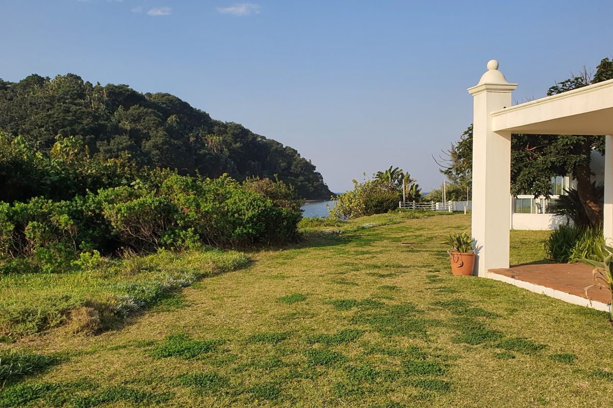 A view of the rear garden and covered patio area, featuring a scenic outlook towards the coastal landscape.