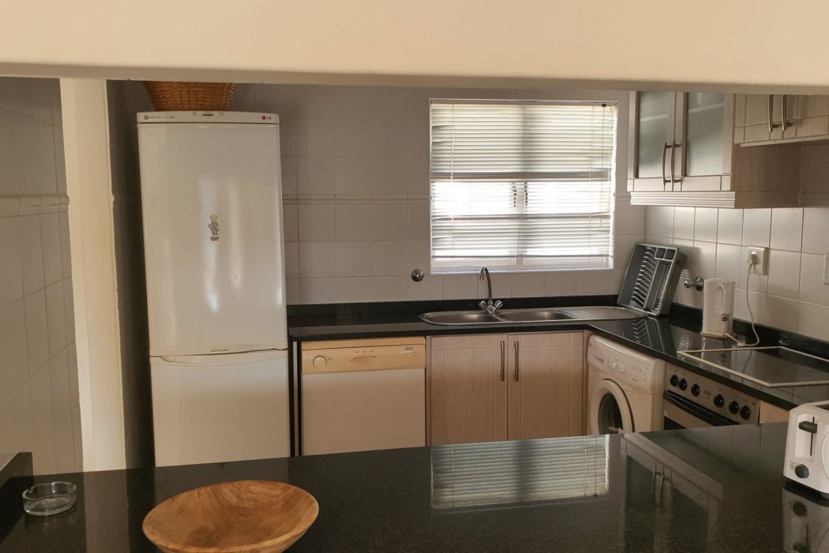 Functional kitchen featuring granite countertops, tiled backsplash, and built-in cabinetry with integrated appliances, offering a practical layout for daily meal preparation.