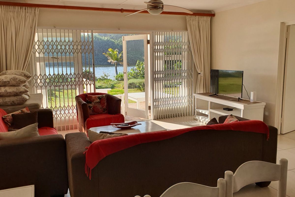 A comfortable living room featuring tiled flooring, a ceiling fan, and large sliding glass doors that open to a scenic outdoor view.