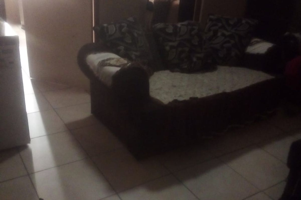 A dimly lit living room area featuring tiled flooring and a doorway leading to an adjacent space.