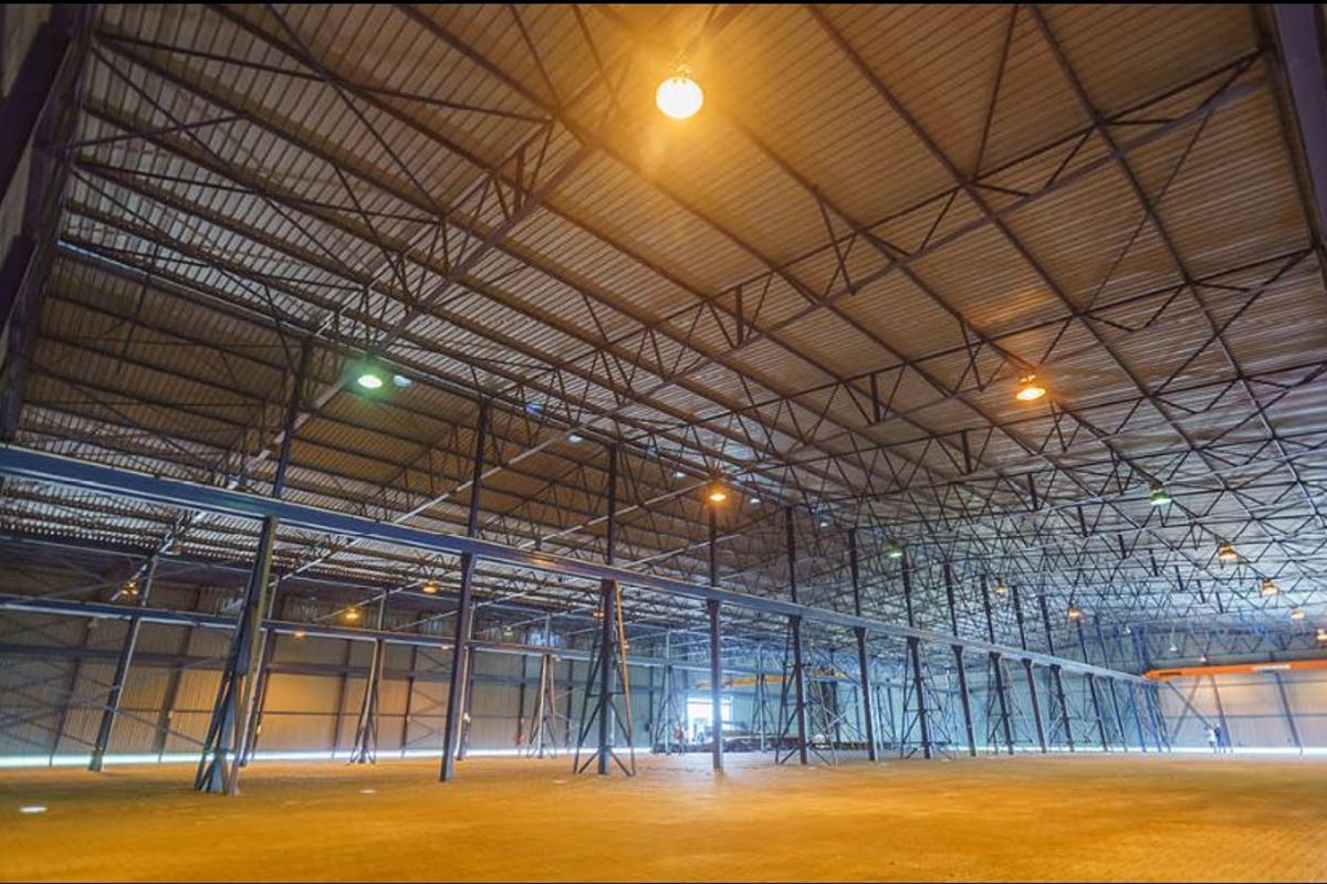 Expansive industrial warehouse space featuring high-clearance steel truss roofing, robust support columns, and durable concrete flooring, suitable for various commercial or storage operations.