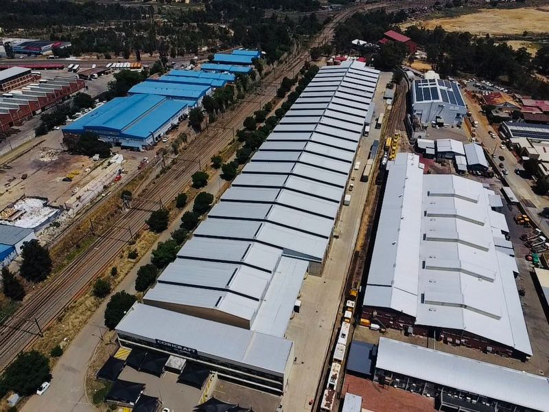 Aerial view of a large industrial warehouse complex featuring extensive metal roofing, dedicated loading areas, and direct access to adjacent railway infrastructure.