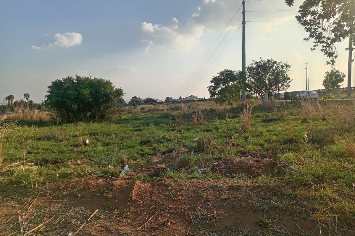 A view of a vacant residential plot featuring natural grass coverage and utility infrastructure.