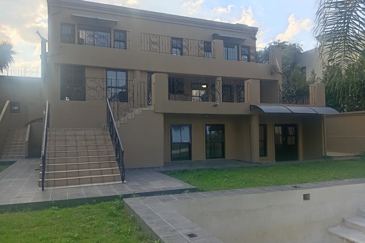 Rear view of a multi-level house featuring a swimming pool, tiled patio area, and upper-level balconies with wrought iron railings.