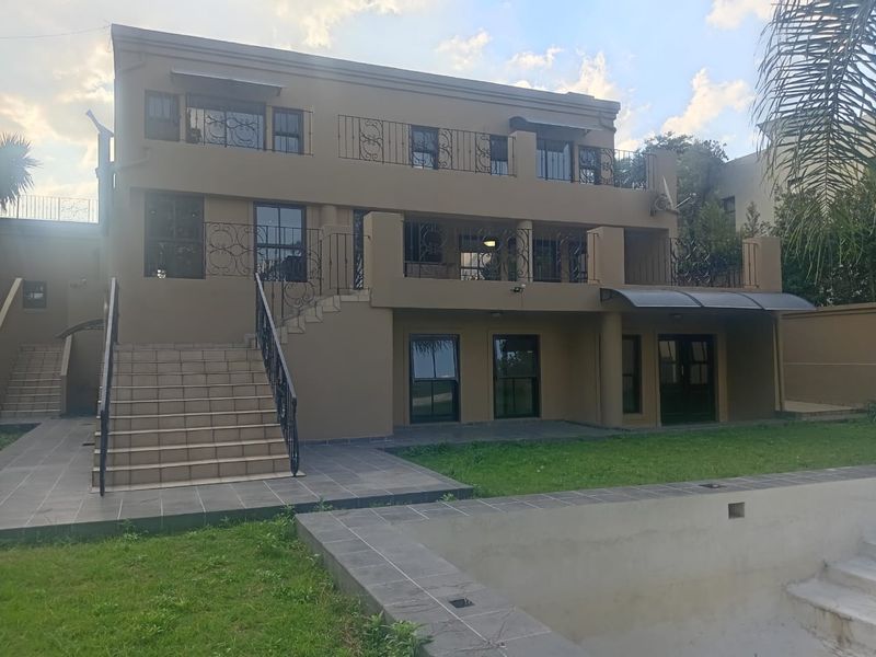 Rear view of a multi-level house featuring a swimming pool, tiled patio area, and upper-level balconies with wrought iron railings.