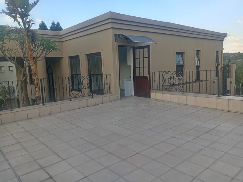 A spacious outdoor balcony featuring tiled flooring, a wrought iron balustrade, and direct access to the interior through a timber door.