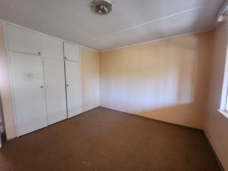An empty bedroom featuring built-in cupboards, carpeted flooring, and neutral wall finishes, offering a blank canvas for renovation or staging.