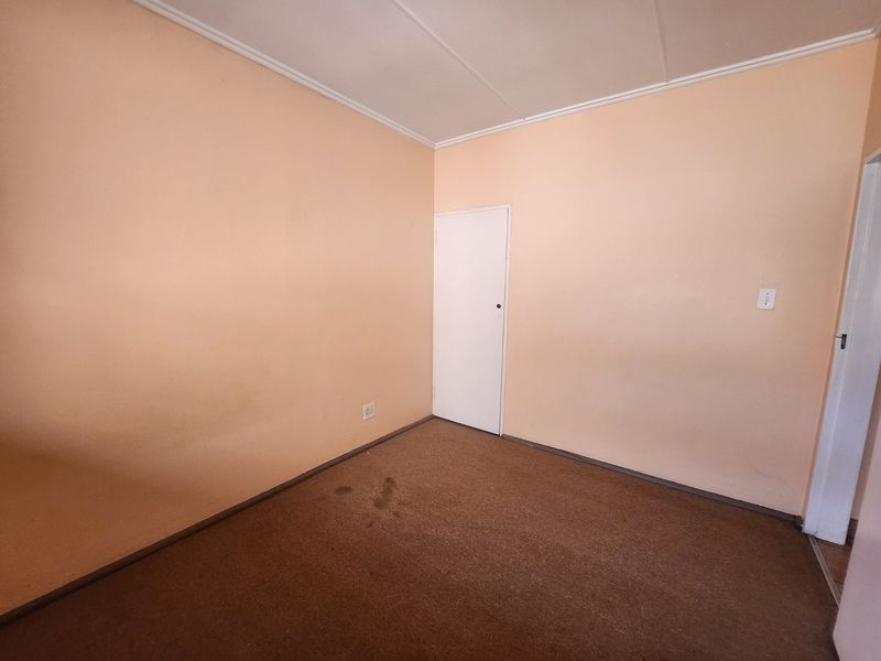 An empty bedroom featuring carpet flooring, coved ceilings, and neutral wall finishes, offering a blank canvas for potential renovation or staging.