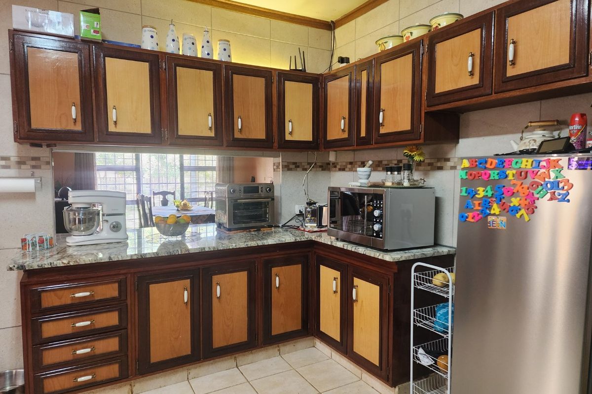 A functional kitchen featuring granite countertops, tiled backsplash, and traditional two-tone wooden cabinetry with ample storage space.