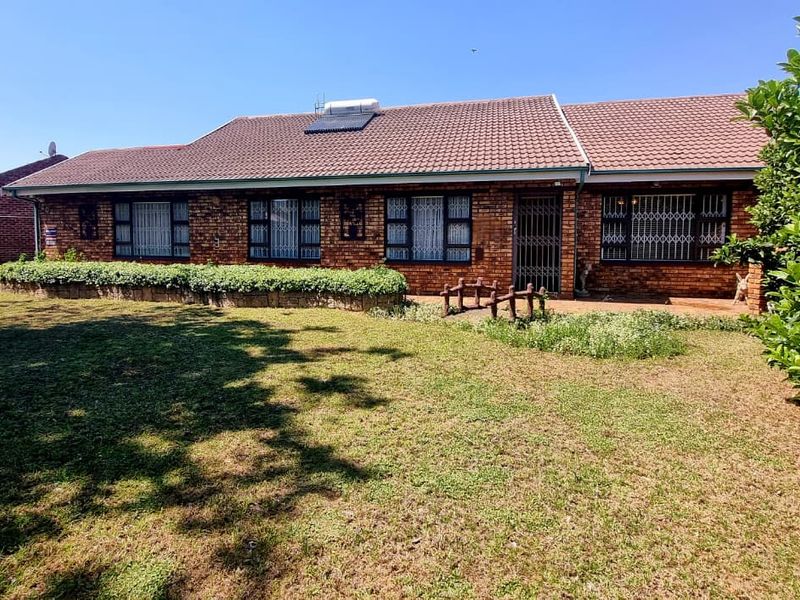 A single-story brick house featuring a tiled roof, solar water heater, and security bars on windows, set within a well-maintained front garden.