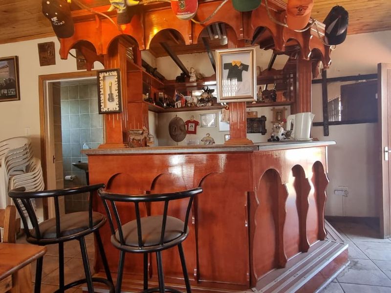 A dedicated bar area featuring a traditional timber bar counter, wood-paneled ceiling, and tiled flooring, offering a classic entertainment space.