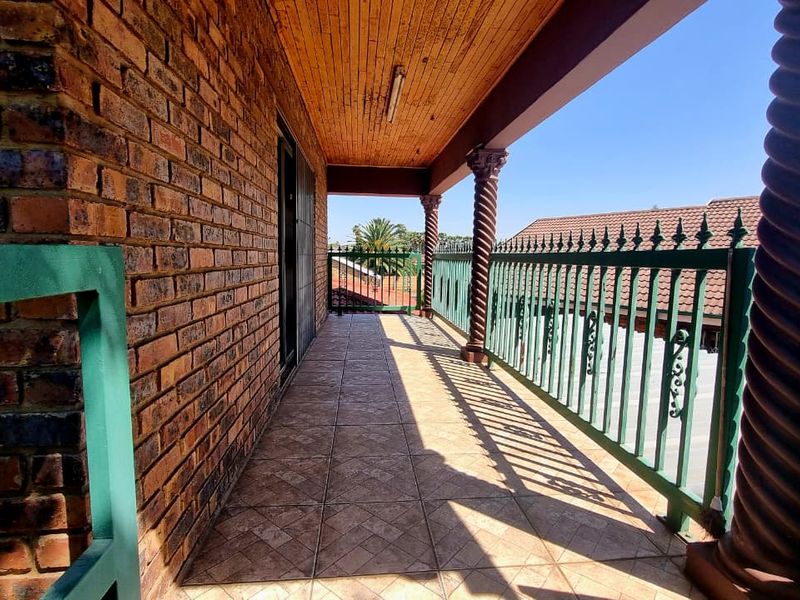 A covered balcony featuring exposed brickwork, decorative spiral columns, and a timber ceiling, offering a classic outdoor space for relaxation.