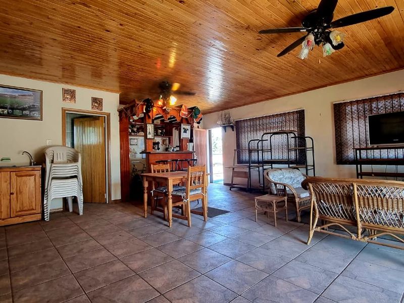 Spacious open-plan living area featuring a timber ceiling, tiled flooring, and a built-in bar, offering a versatile layout for entertainment and relaxation.