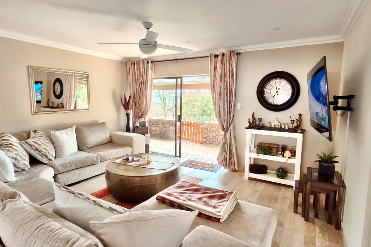 A comfortable living room featuring tiled flooring, a ceiling fan, and sliding glass doors that provide direct access to an outdoor patio area.