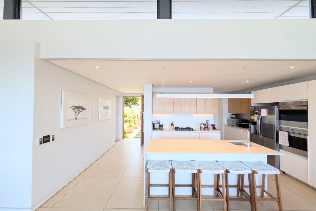 Modern open-plan kitchen featuring a central island, built-in appliances, sleek cabinetry, and high-level clerestory windows providing ample natural light.