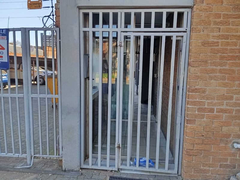 Exterior view of the apartment entrance featuring a metal security gate and brick facade.
