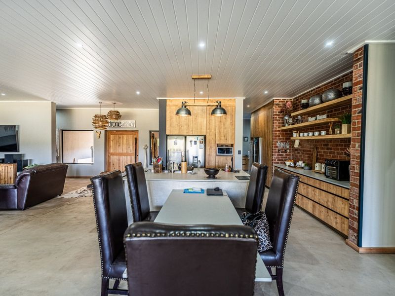 Spacious open-plan living and kitchen area featuring exposed brick walls, modern timber cabinetry, a central kitchen island, and polished concrete flooring.