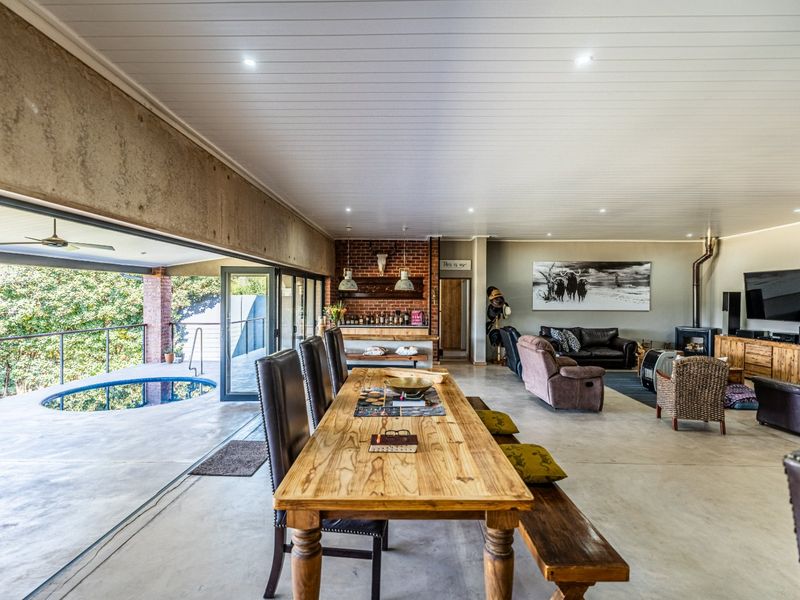 Spacious open-plan living and dining area featuring polished concrete floors, a brick fireplace, and seamless indoor-outdoor flow to the pool deck.