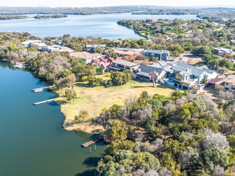 Aerial view of a waterfront residential estate featuring expansive green lawns, private jetty access, and scenic lake views.