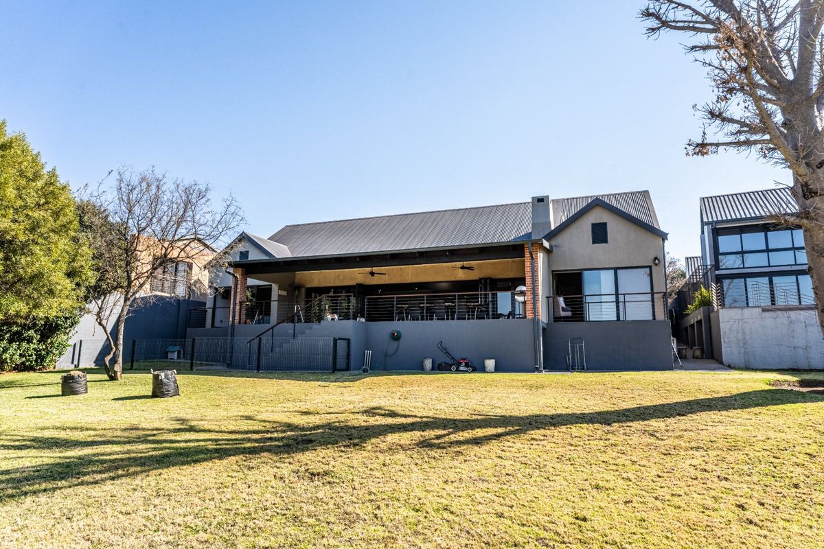 Rear view of the property featuring a spacious covered patio, metal roofing, and large sliding glass doors overlooking the backyard lawn.