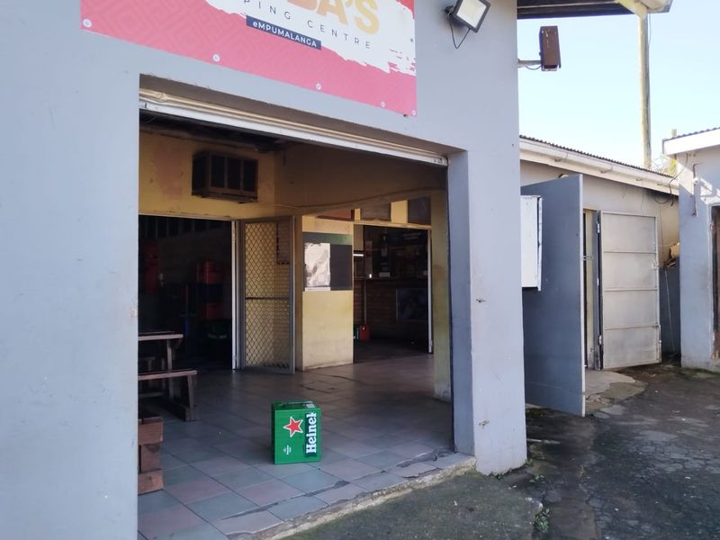 Front entrance view of a commercial retail unit featuring tiled flooring, security gate, and exterior signage.