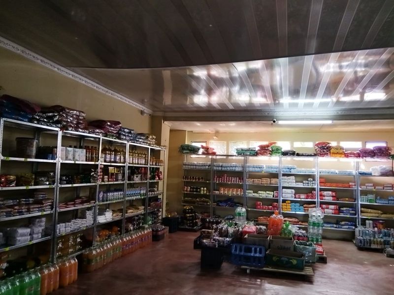 Commercial retail space featuring open shelving units, a suspended ceiling, and fluorescent lighting, suitable for general inventory storage or retail operations.