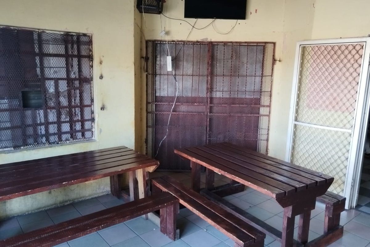 A covered outdoor patio area featuring tiled flooring and security mesh screens, currently showing signs of wear and requiring maintenance.