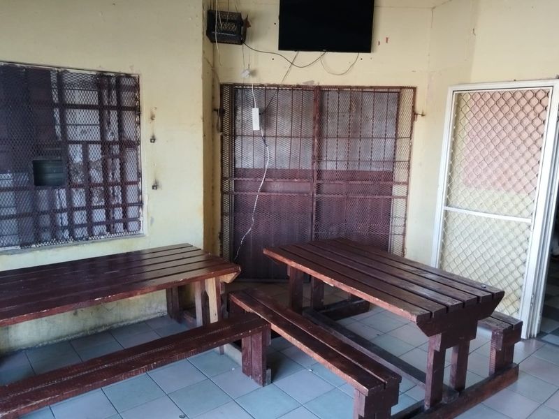 A covered outdoor patio area featuring tiled flooring and security mesh screens, currently showing signs of wear and requiring maintenance.