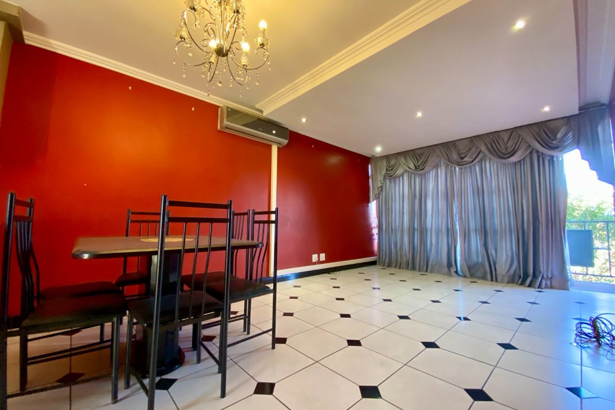 Spacious living area featuring tiled flooring, recessed downlighting, and a split-system air conditioner, with direct access to an outdoor balcony through sliding glass doors.